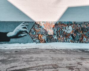 Colorful mural featuring a hand unveiling vibrant graffiti on a street wall.