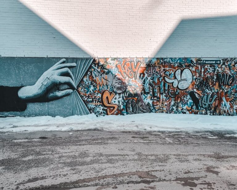 Colorful mural featuring a hand unveiling vibrant graffiti on a street wall.