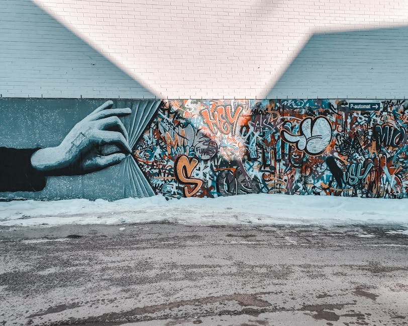 Colorful mural featuring a hand unveiling vibrant graffiti on a street wall.