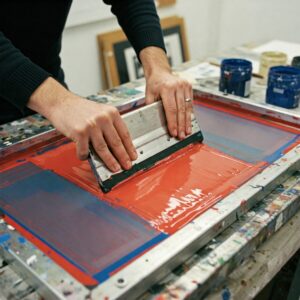 Andy Warhol’s Style: The Art of Fame, Repetition, and the Everyday 4 Hands working on Andy Warhol-style silkscreen print, demonstrating mechanical art production and slight printing imperfections.